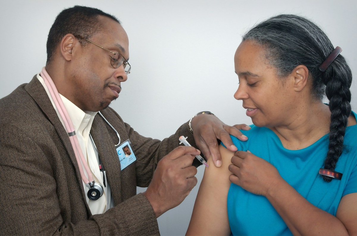 A woman receiving a flu shot from a medical professional 