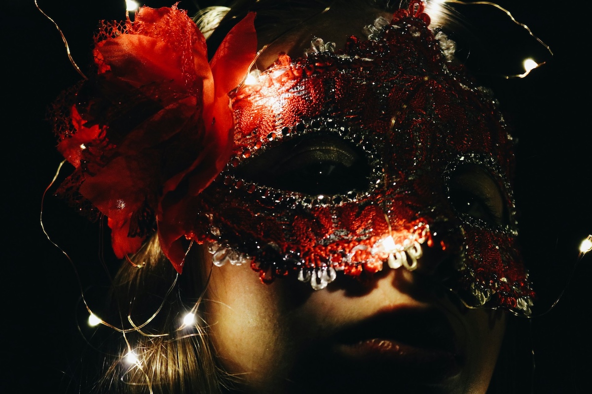 A woman wearing a sparkly red masquerade mask 