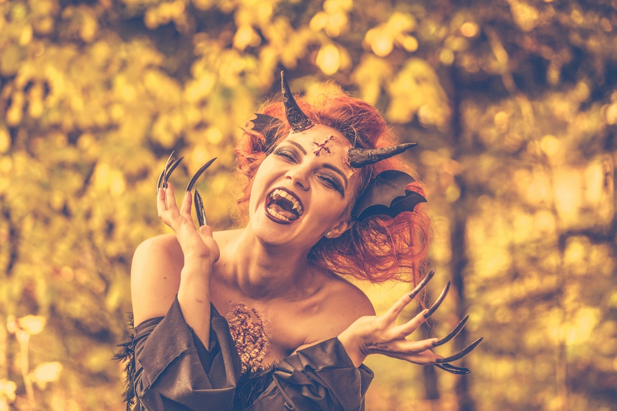 A woman dressed a demon with fangs, horns, and talons for Halloween