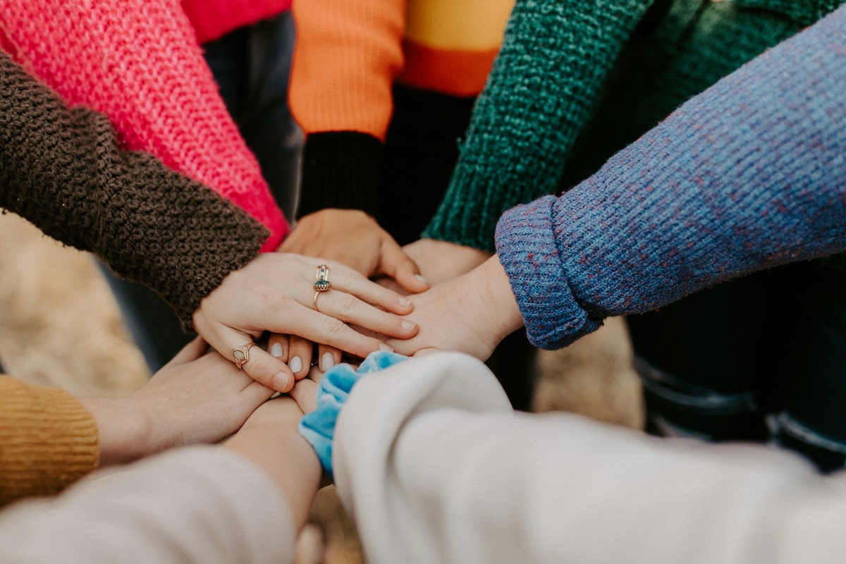 A group of people with their arms extended to place their hands on top of the other